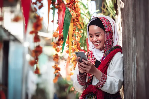 A player using their smartphone during a festive local event, representing RAJ123’s fully mobile-friendly casino.
